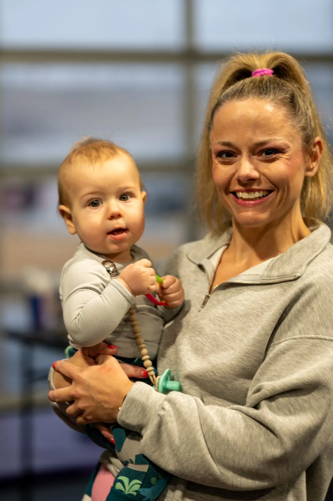 A member holding her baby and smiling on the gym floor