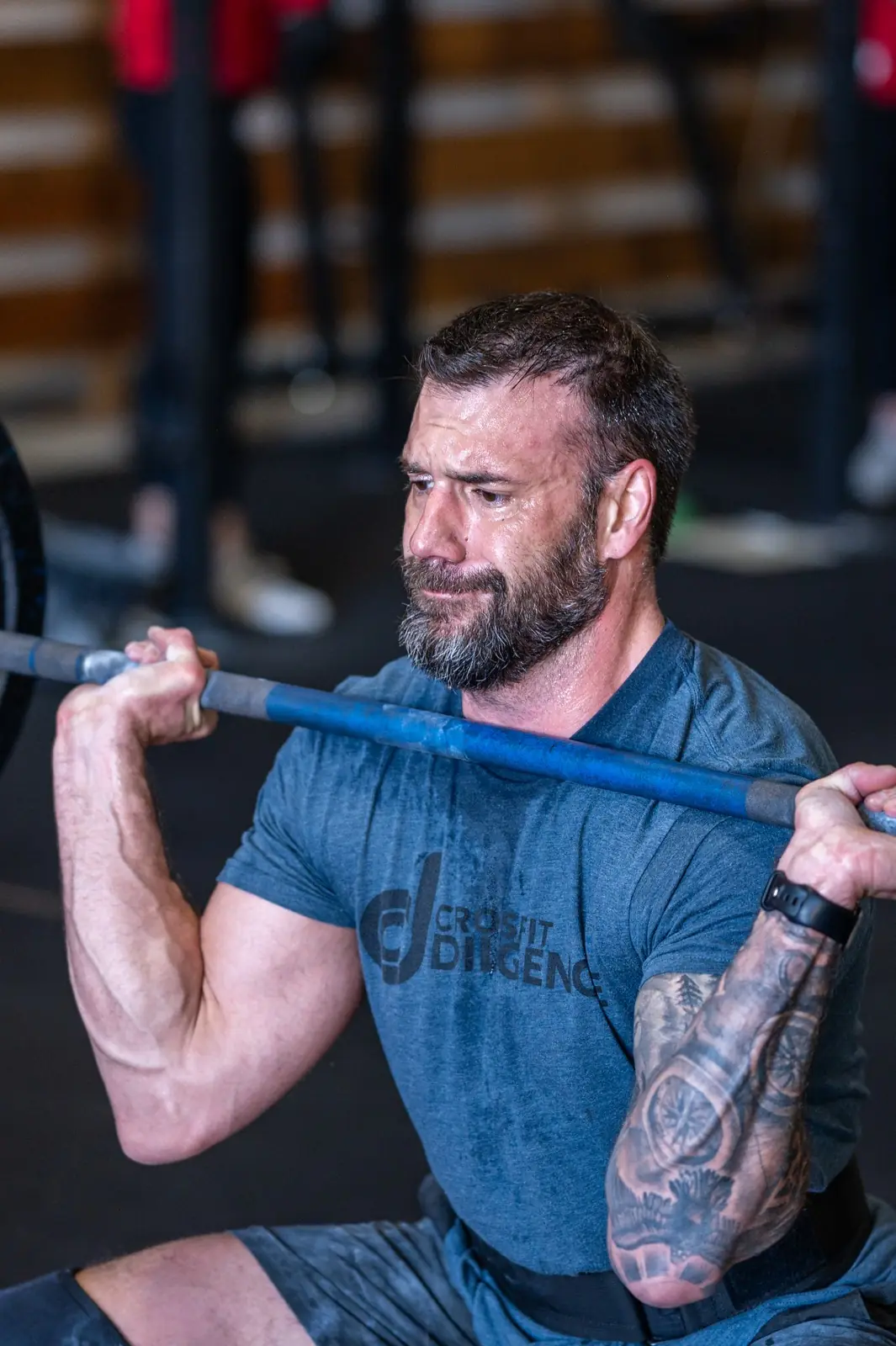 A member in a CrossFit Diligence shirt grinding through a front rack squat