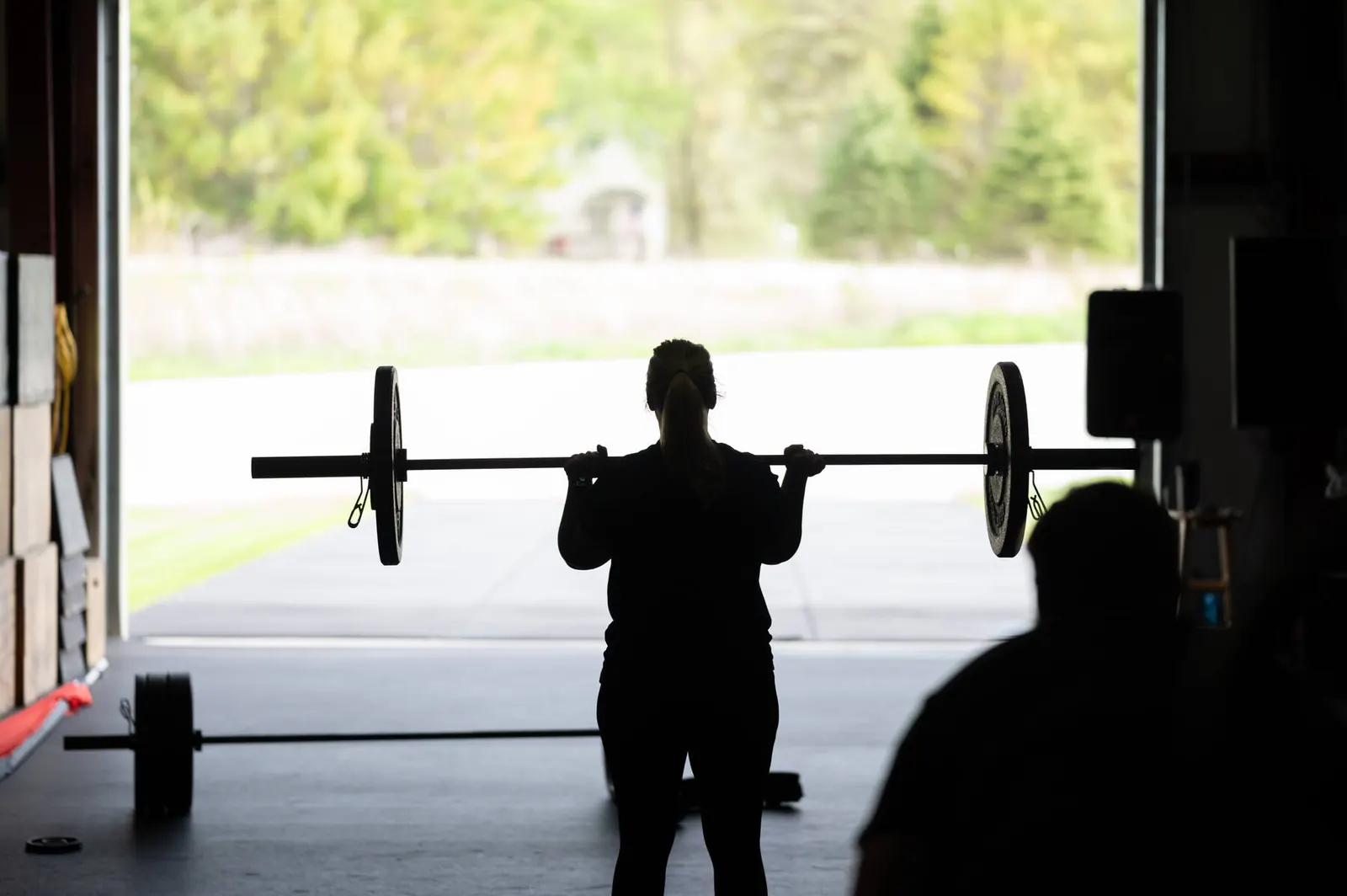 An athlete pressing a weight overhead in the open bay door