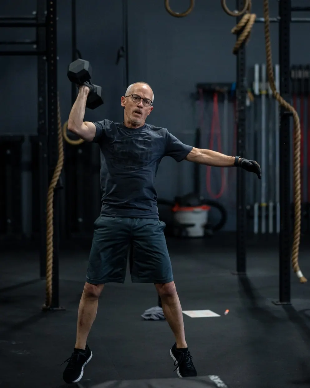 A member swinging a dumbbell overhead