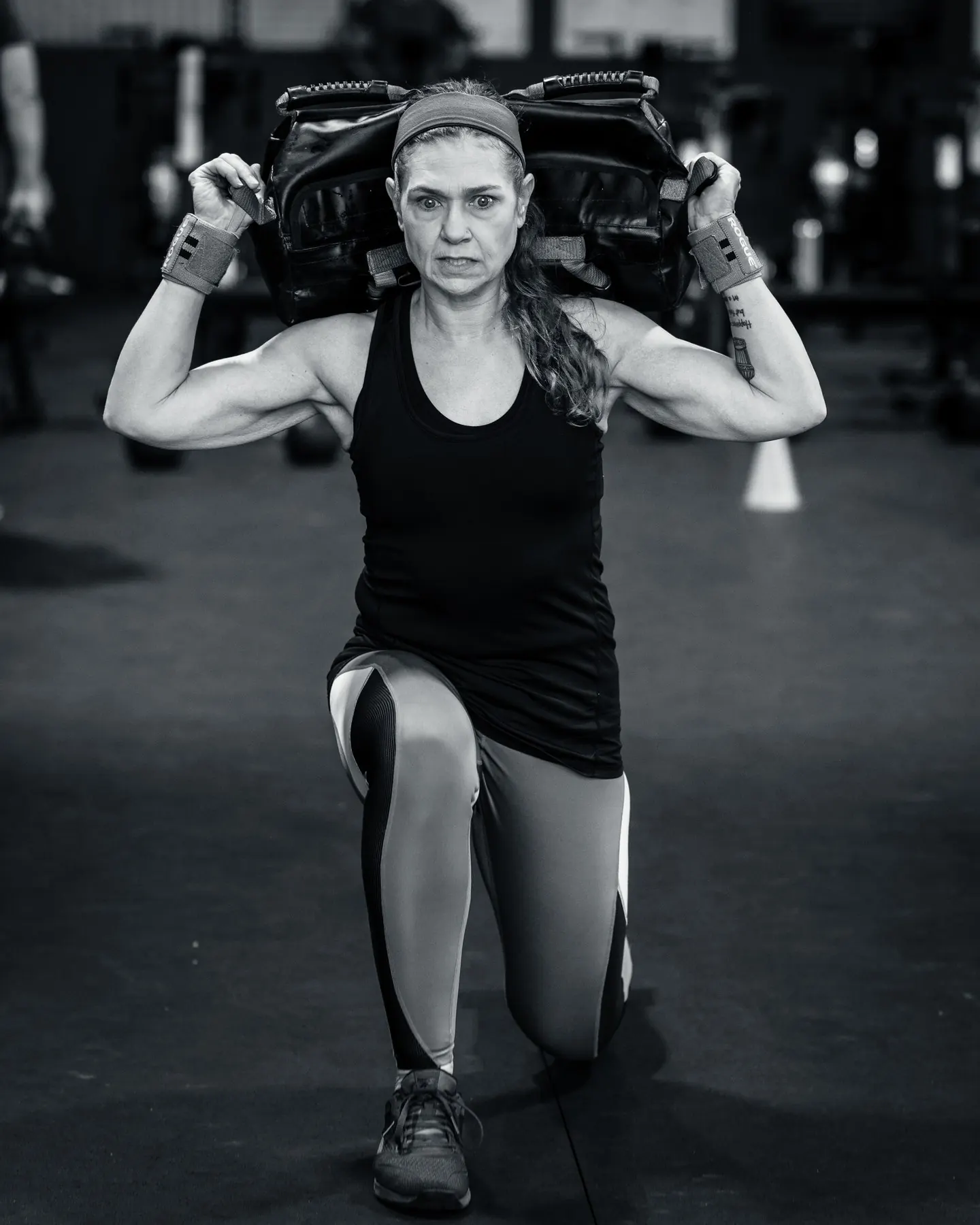 A member in a lunge with a sandbag across her shoulders