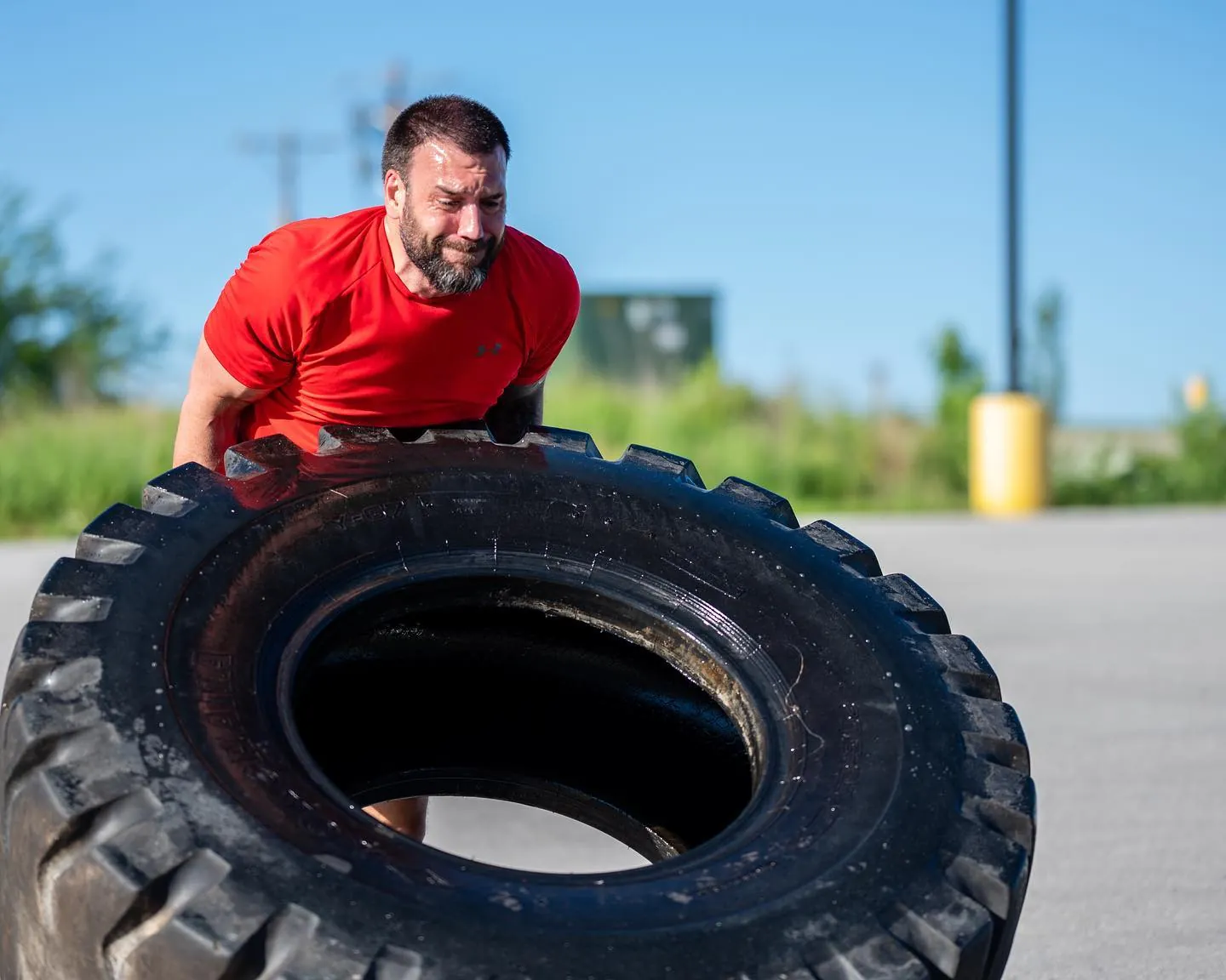 A member flipping a tractor tire outside the gym