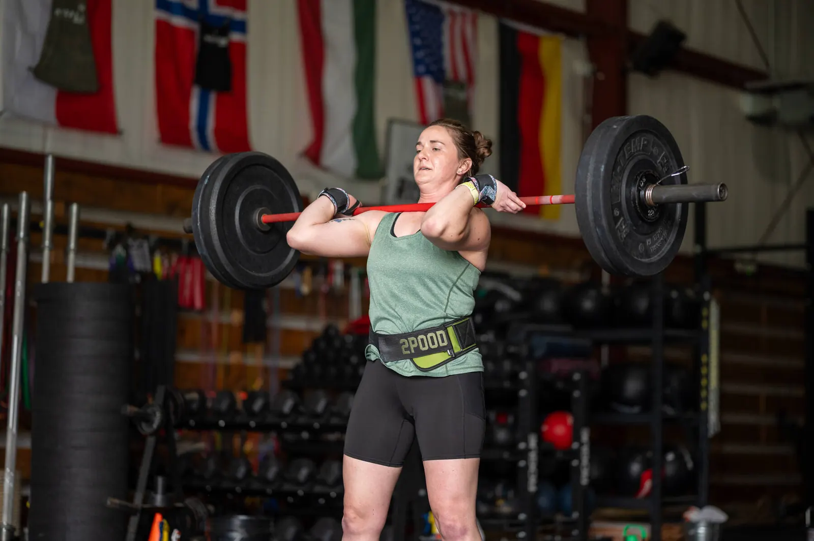 A member driving a loaded barbell overhead